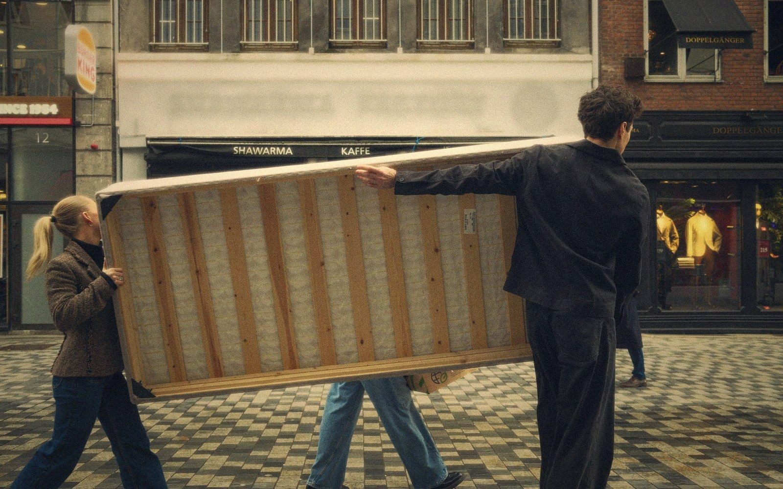 Two people carrying a folding table between cars