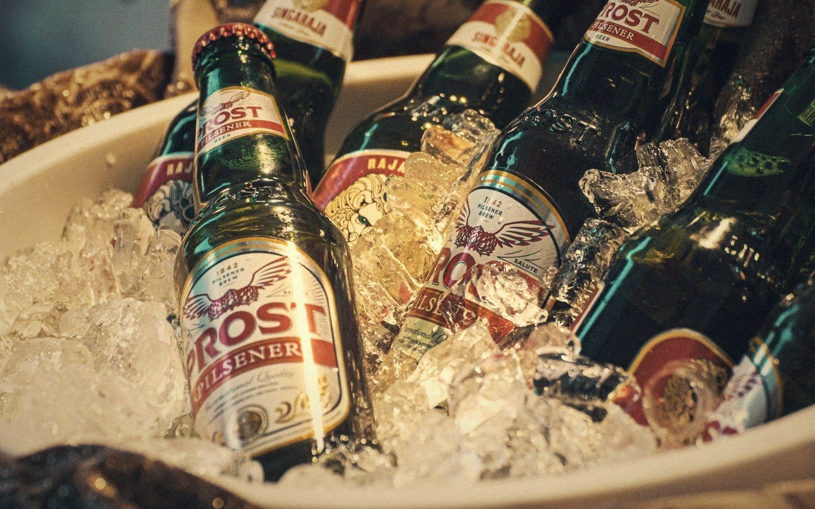 A cooler open with drinks packed in ice, a hand reaching in